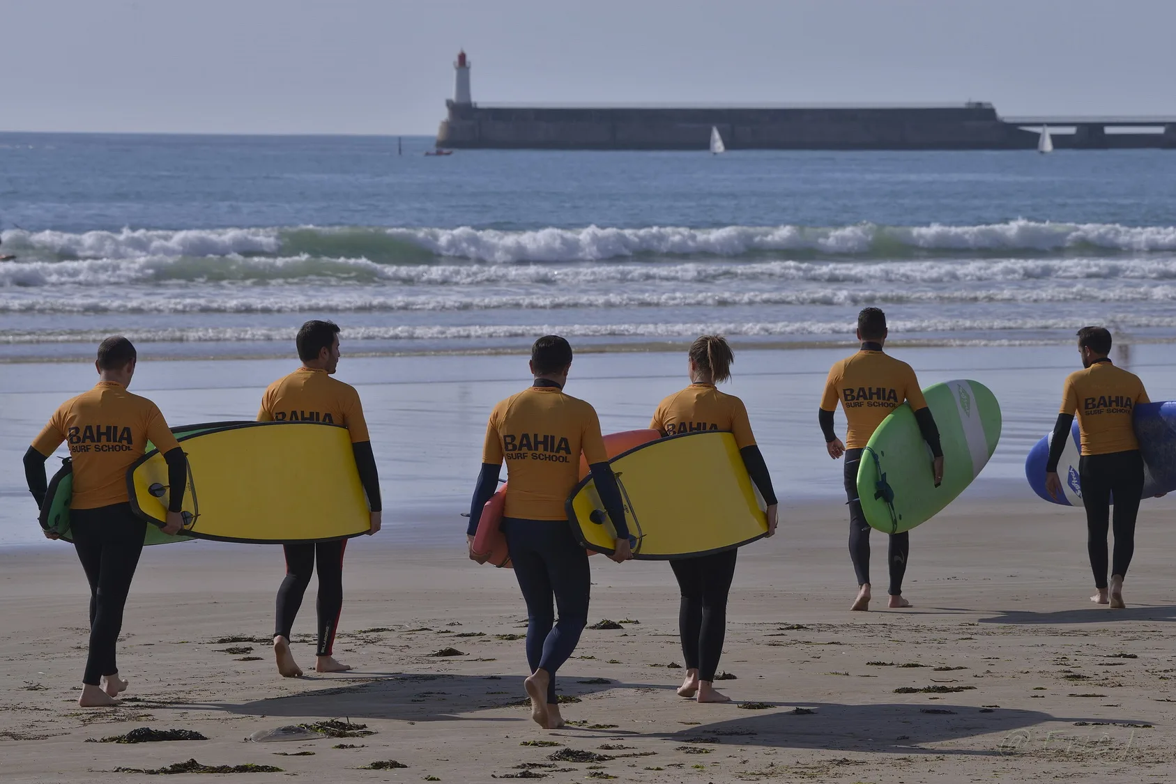 Le groupe en lycra Bahia descend vers l’eau, planches sous le bras.