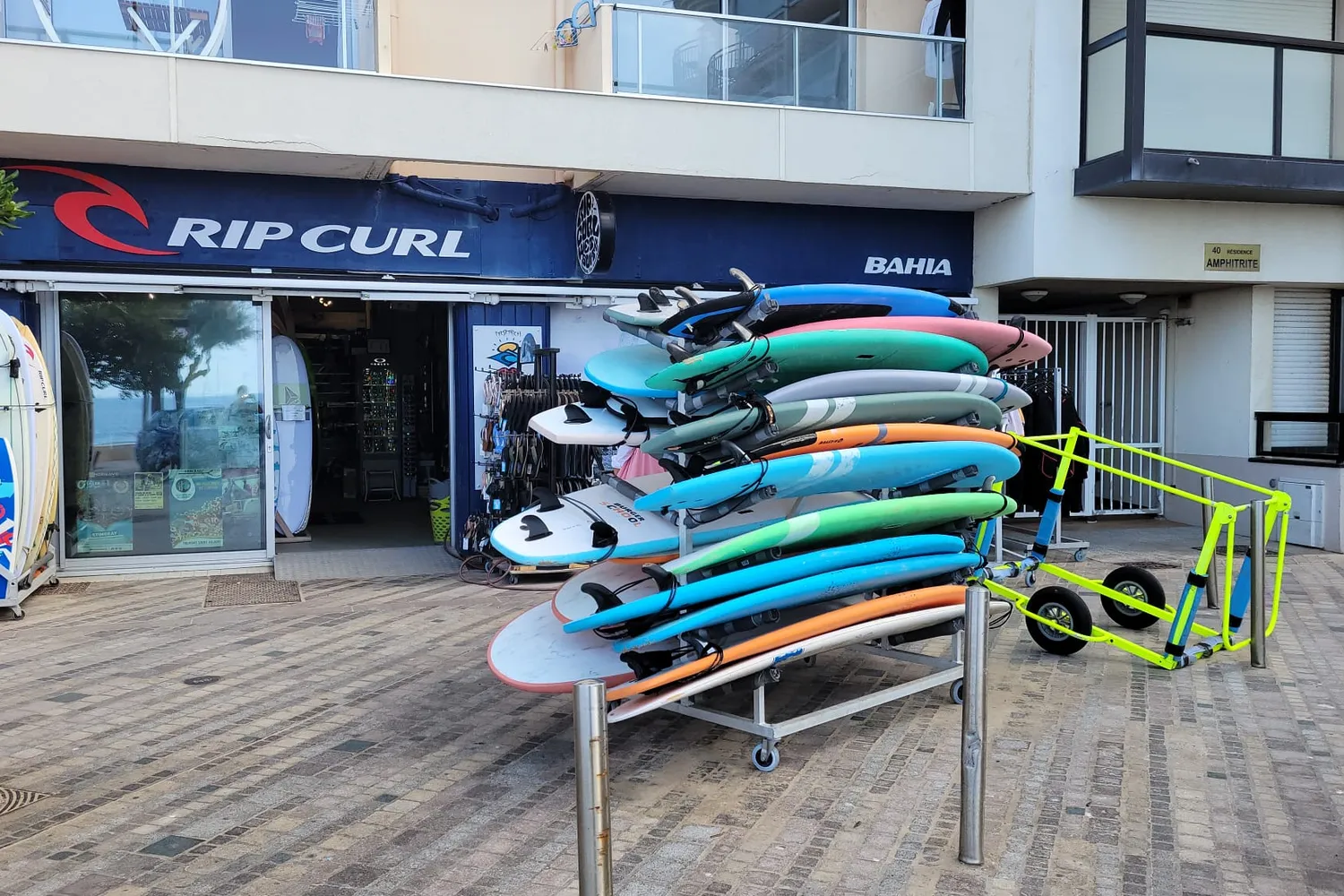 La devanture du magasin sur le remblai, le rack de planches de l’école posé devant.